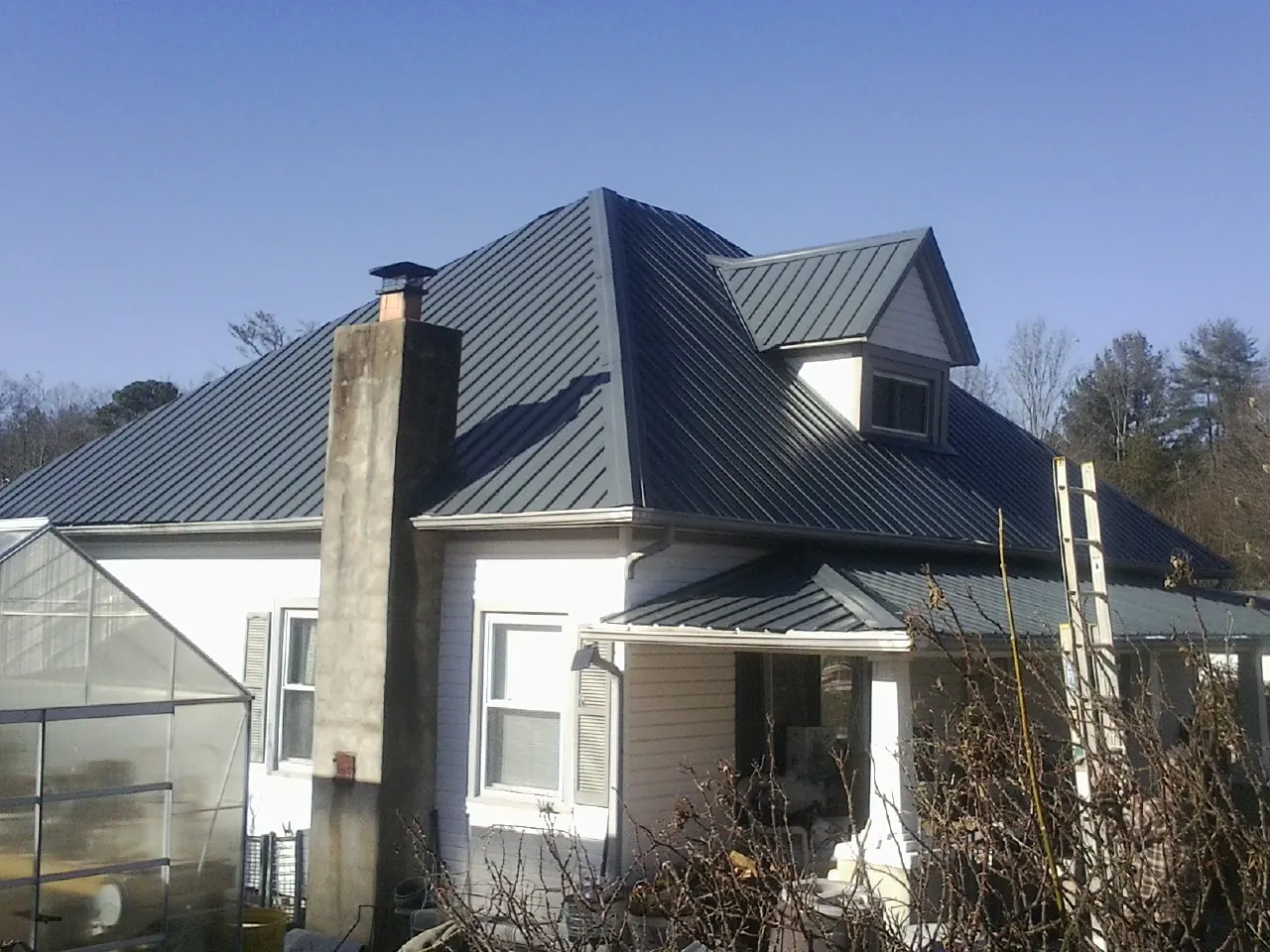 Dark blue standing seam metal roof on a white farmhouse with dormer — Slate & Tile Roof Repair by Roofing Brothers in Kingston Mines