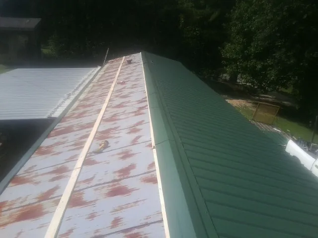 Old rusted panels beside newly installed green metal roofing — Wind Damage Roof Repair by Roofing Brothers in Kingston Mines