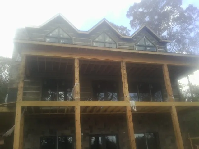 Dormers and porch framing on a large log home under construction — Roof Coating work by our crew in Kingston Mines