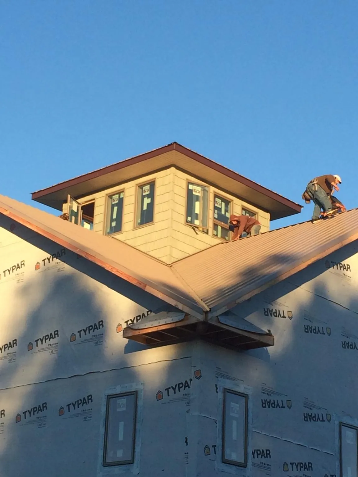 Roofers working around a rooftop cupola on a new metal roof at sunset — Roof Waterproofing in Kingston Mines by Roofing Brothers